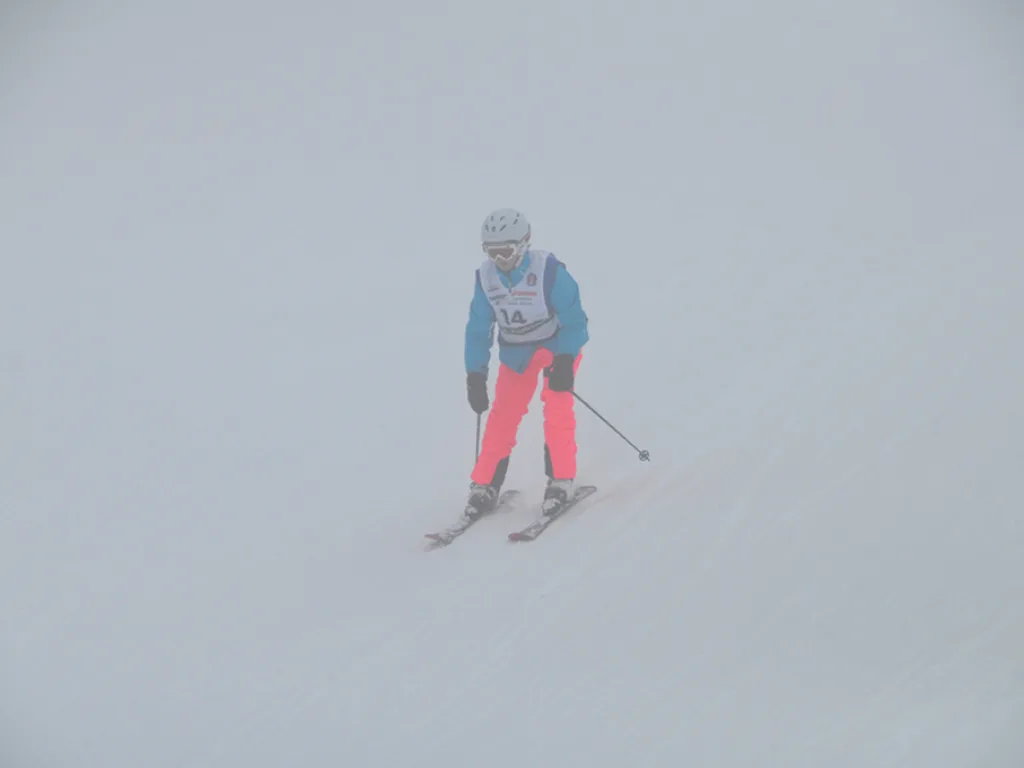 Skifahrerin in pinker Hose auf der Strecke.